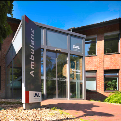 Eingang der Ambulanz der LWL-Klinik Herten mit Glasfassade und rotem Backsteingebäude im Hintergrund. Links steht ein großes Schild mit der Aufschrift ‚Ambulanz‘ und dem LWL-Logo. Eingang der Ambulanz der LWL-Klinik Herten mit Glasfassade und rotem Backsteingebäude im Hintergrund. Links steht ein großes Schild mit der Aufschrift ‚Ambulanz‘ und dem LWL-Logo.